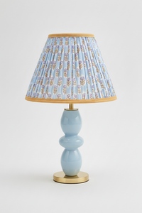 10-inch pleated blockprint empire lampshade with sky blue daisy pattern, mounted on light blue ceramic table lamp with golden base