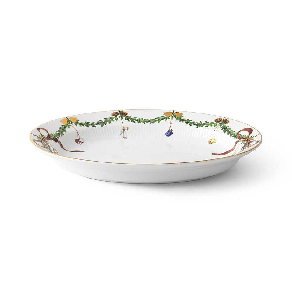 Angled view of Star Fluted Dish Oval porcelain serving dish showcasing historic Danish Christmas decorations on white background