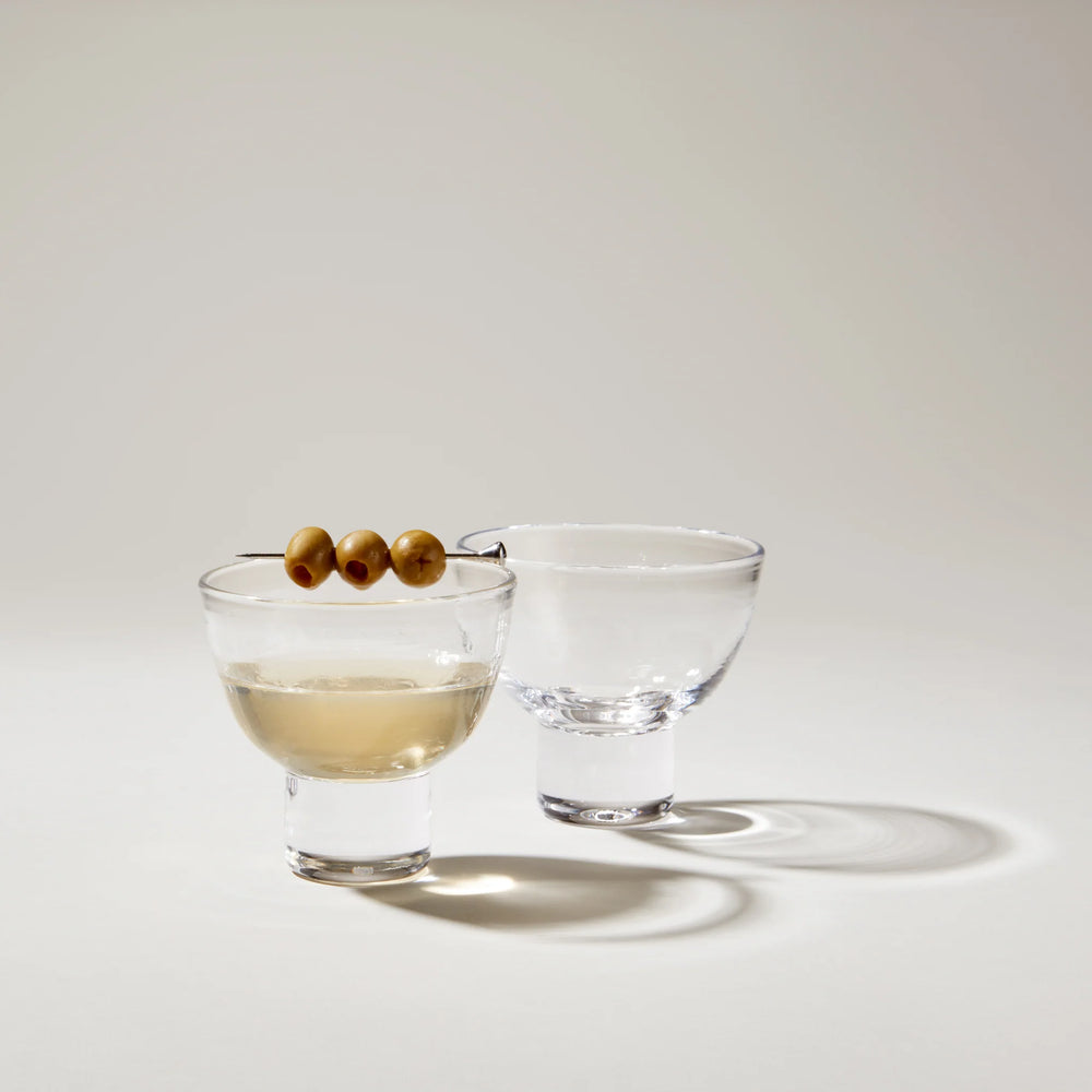 Front view of two Manchester Martini stemless glasses, one with a cocktail and three olives on a pick