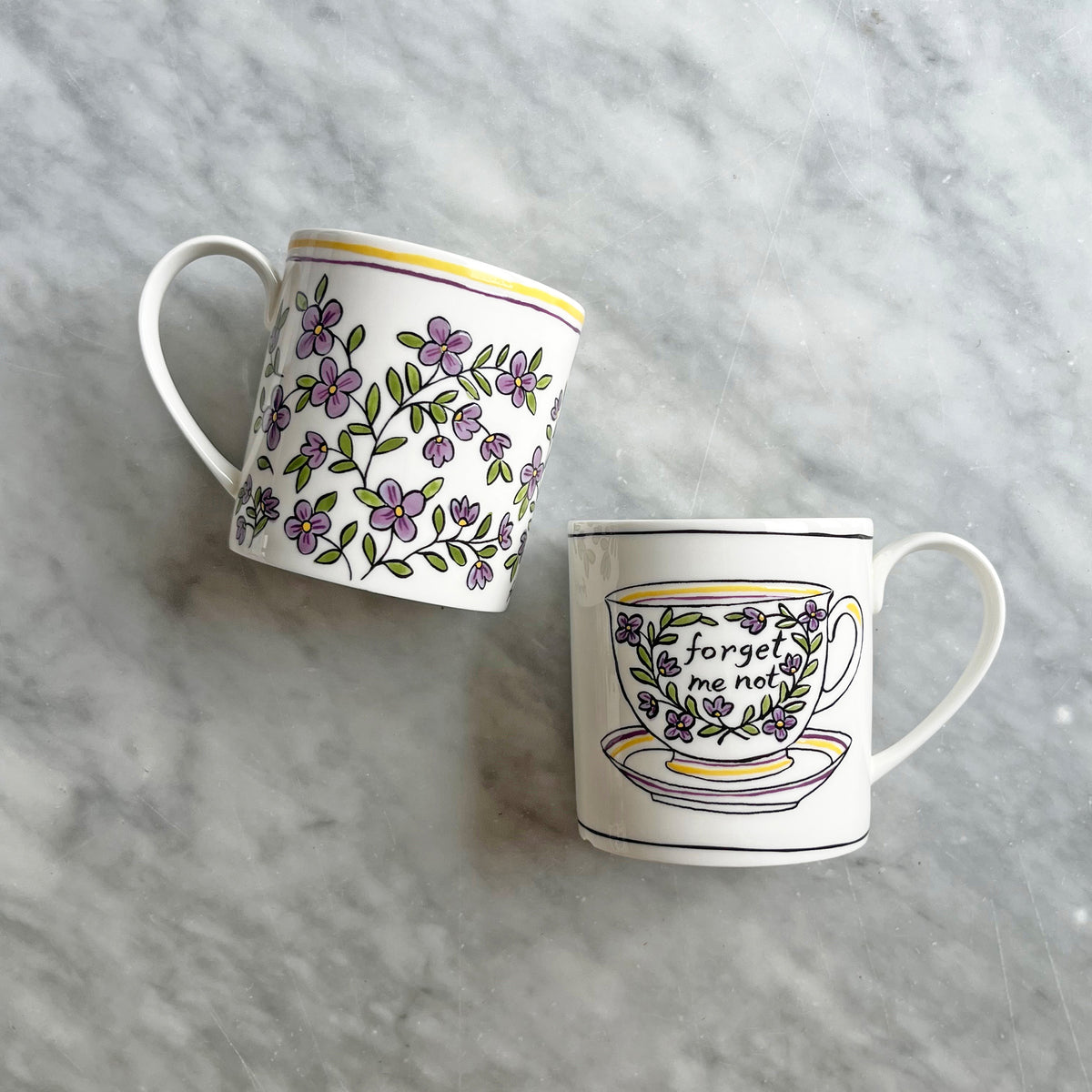 Angled view of Heritage Forget Me Not Mug 2 showcasing purple floral decals and colored rim on a gray background