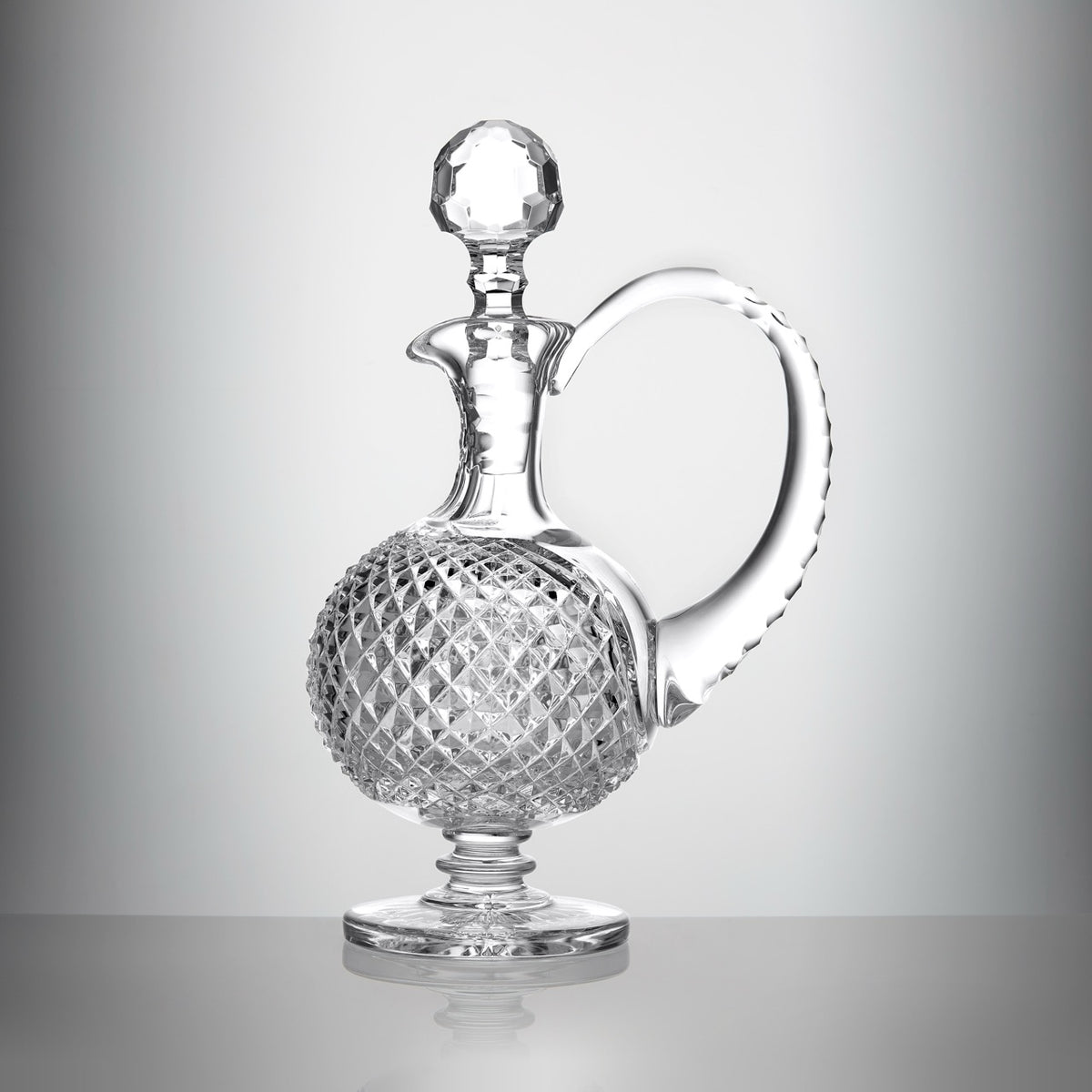 Front view of the Mastercraft Heritage Claret Decanter showcasing its diamond-cut crystal body and swooping handle against a gray background