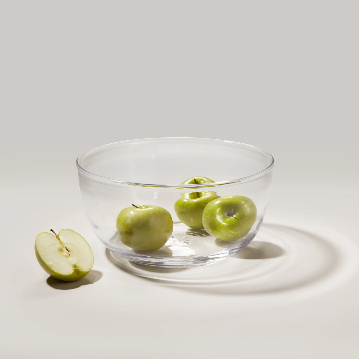 Front view of Walden Bowl showcasing its clear glass and wide rounded shape with green apples on a white surface