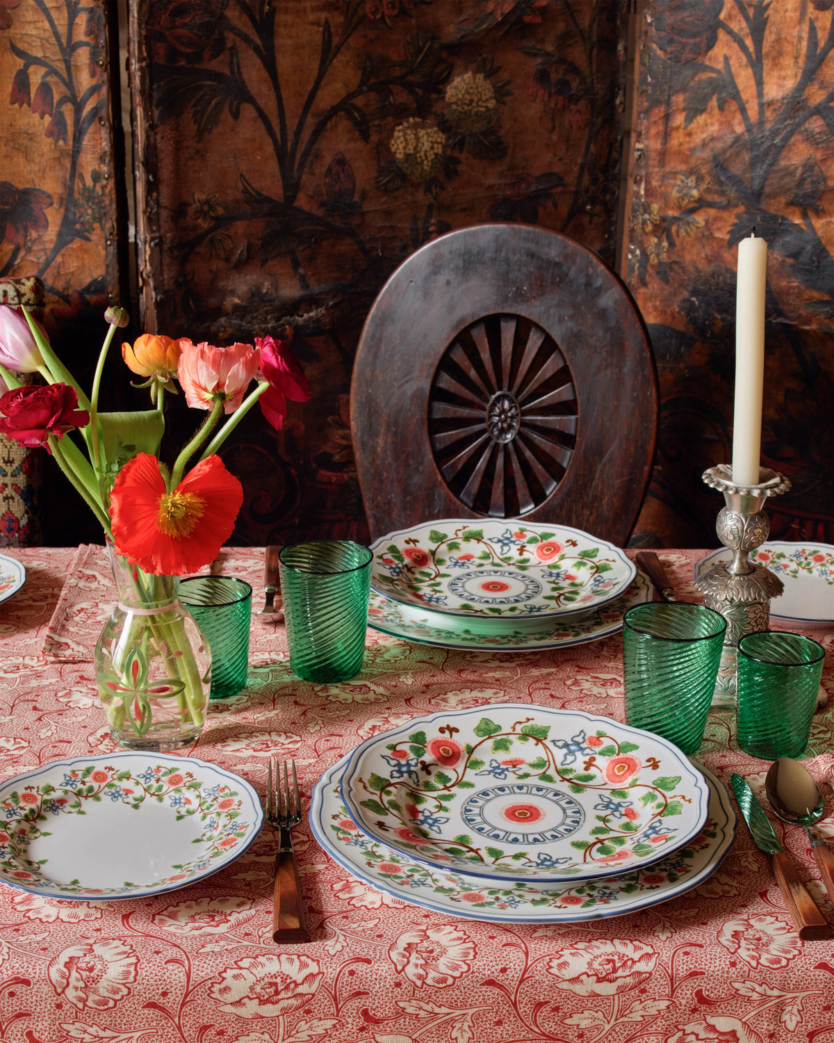 Toscana Red Tablecloth styled on a dining table with floral plates, green glasses, flowers, and candles