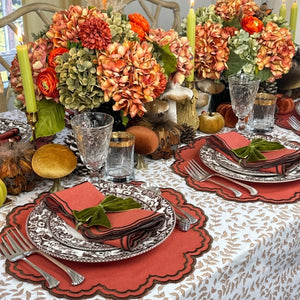 An autumn-themed table setting featuring burnt orange scalloped placemats and  matching napkins with brown embroidery, Thanksgiving table, luxury placemats