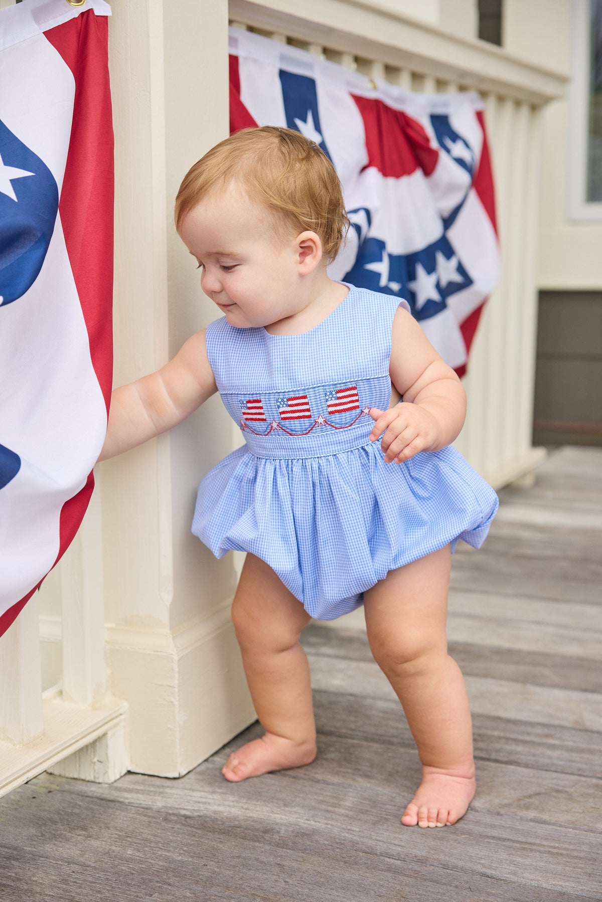 Little English traditional children's clothing.  Sleeveless bubble in royal blue mini check fabric and smocking at the chest with American flag bunting for baby boys