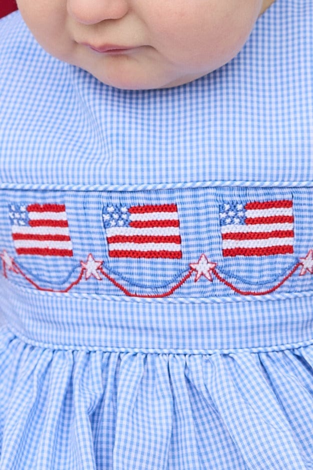 Little English traditional children's clothing.  Sleeveless bubble in royal blue mini check fabric and smocking at the chest with American flag bunting for baby boys