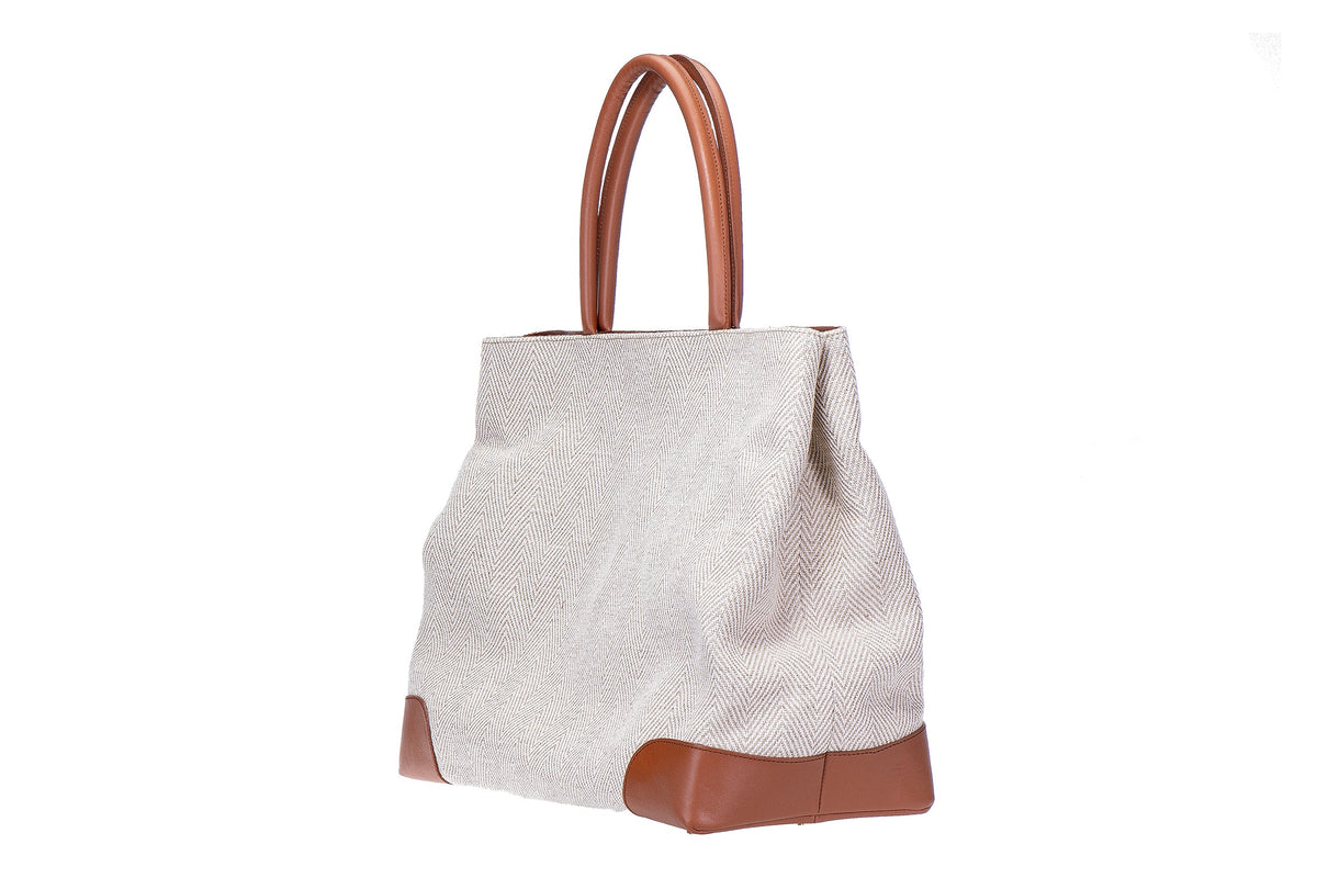 Three-quarter view of Cream Herringbone Tote showcasing cream herringbone fabric with tan leather handles and reinforced leather corners on a white background