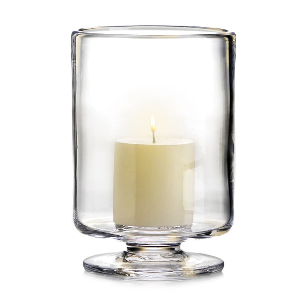 Front view of Nantucket Hurricane glass on pedestal showcasing clear handblown glass and a lit pillar candle against a white background