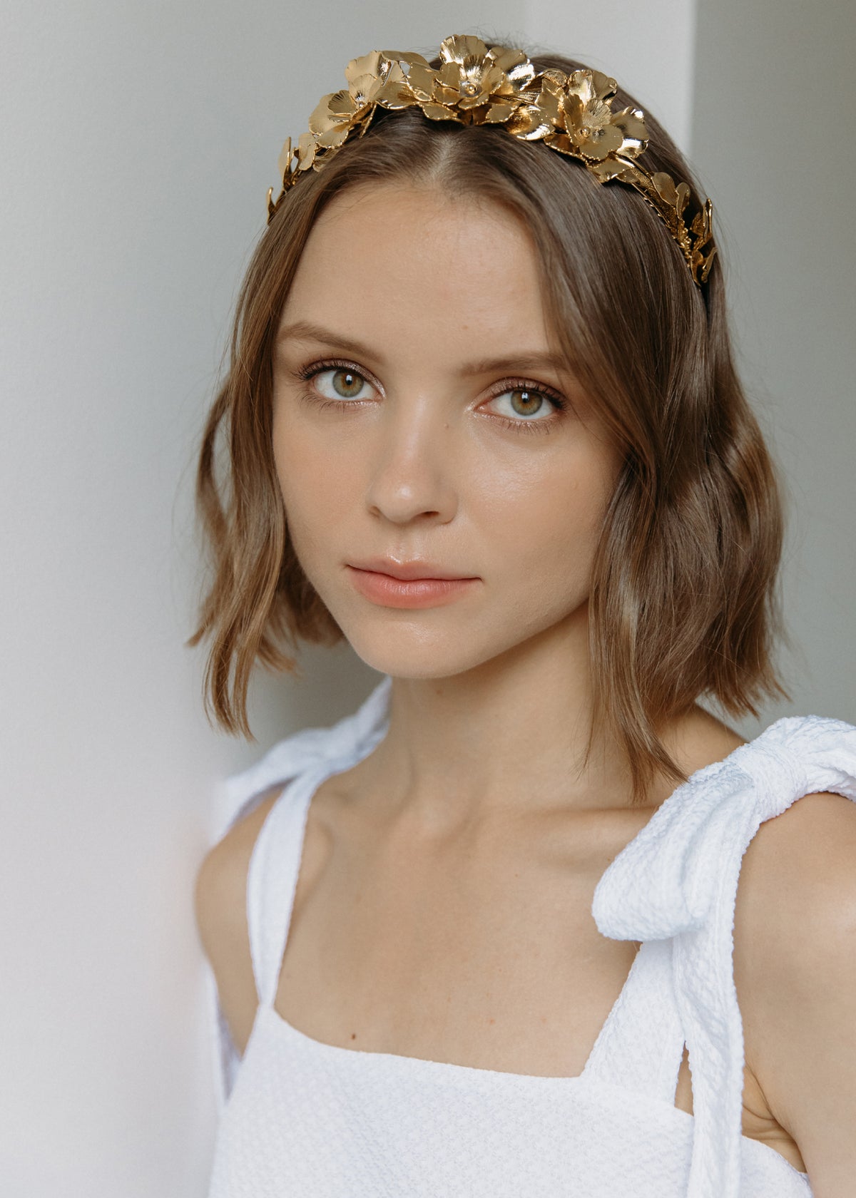 Close-up of Rowena Headband showcasing golden blooms and life-like foliage worn on a model against a light background