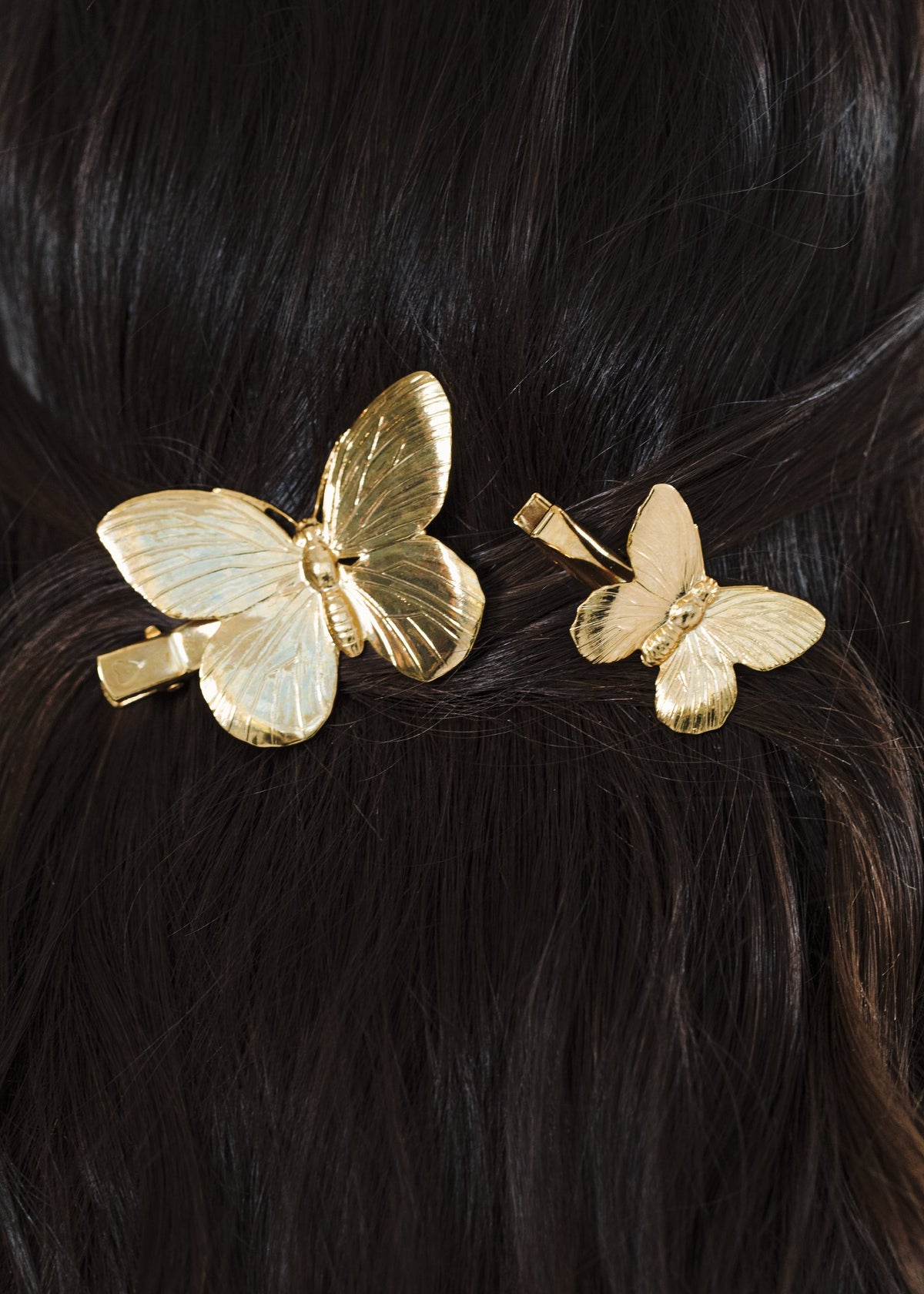 Close-up of Papillion Hair Clips in Gold showcasing butterfly designs and alligator clips against dark hair