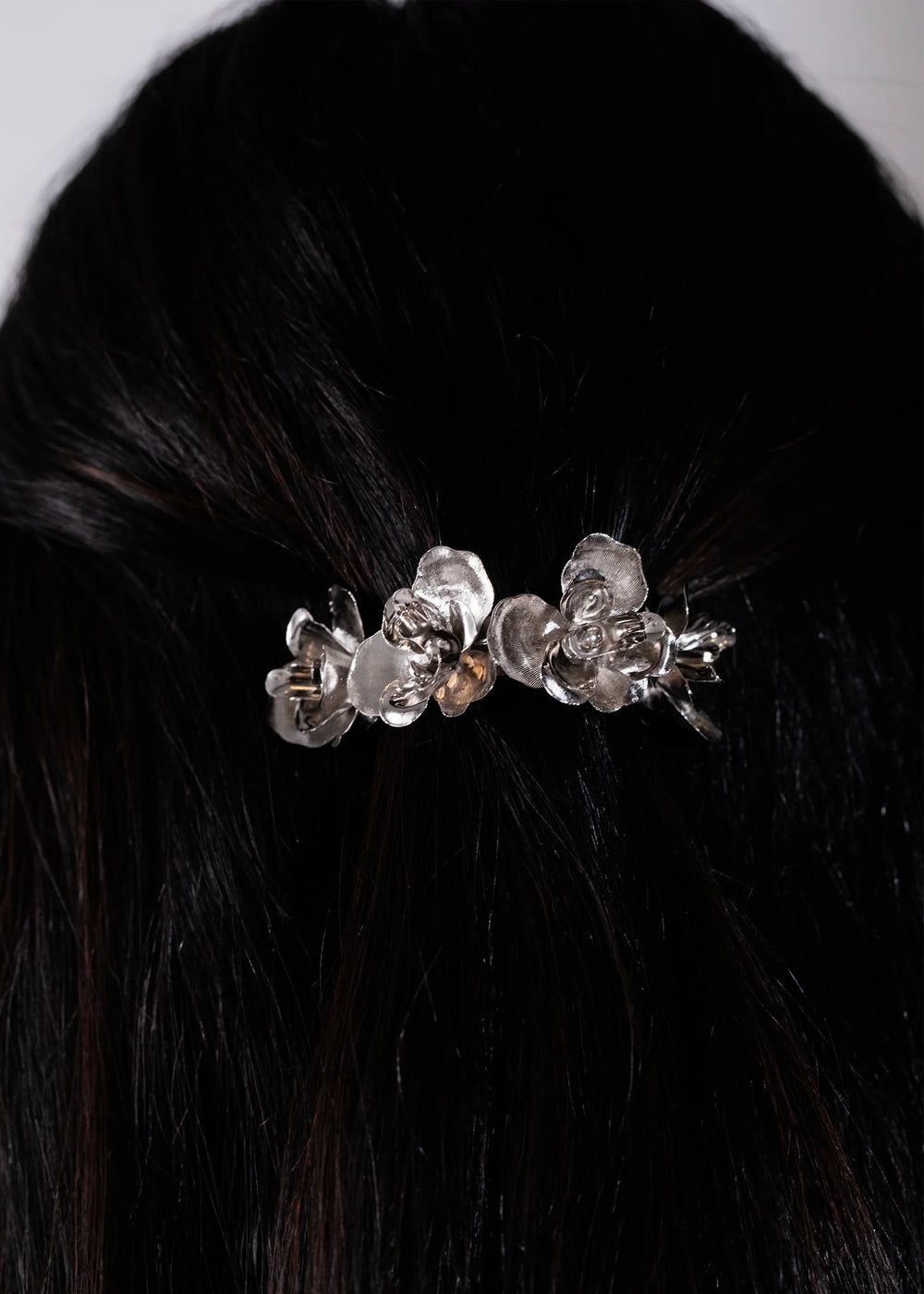 Rear view of Larena Barrette in silver showcasing rhodium-plated floral motifs worn in dark hair