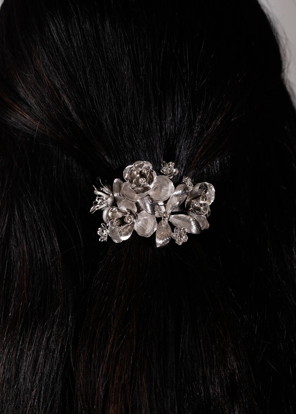 Close-up of Orinda Barrette in Silver showcasing layered geometric floral metalwork on dark hair