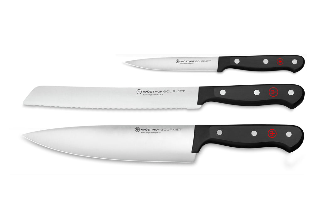 Top view of Wüsthof 3-piece knife set: 8in chef, 8in serrated bread, 4.5in utility with black riveted handles on white background