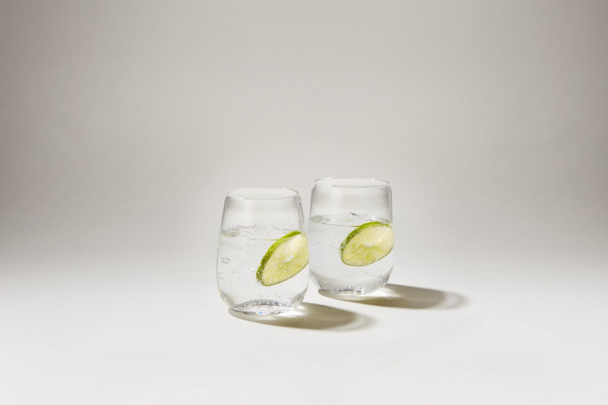 Front view of Woodstock tumbler set of two with clear glass and lime slices on a white background