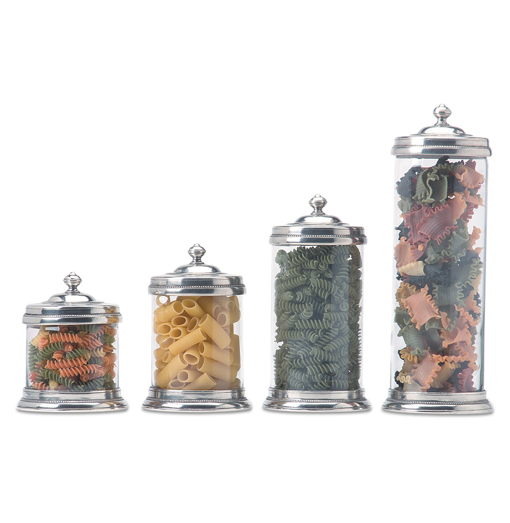 Front view of Glass Canister, Large with clear glass, pewter lid and base, beside smaller canisters on white background