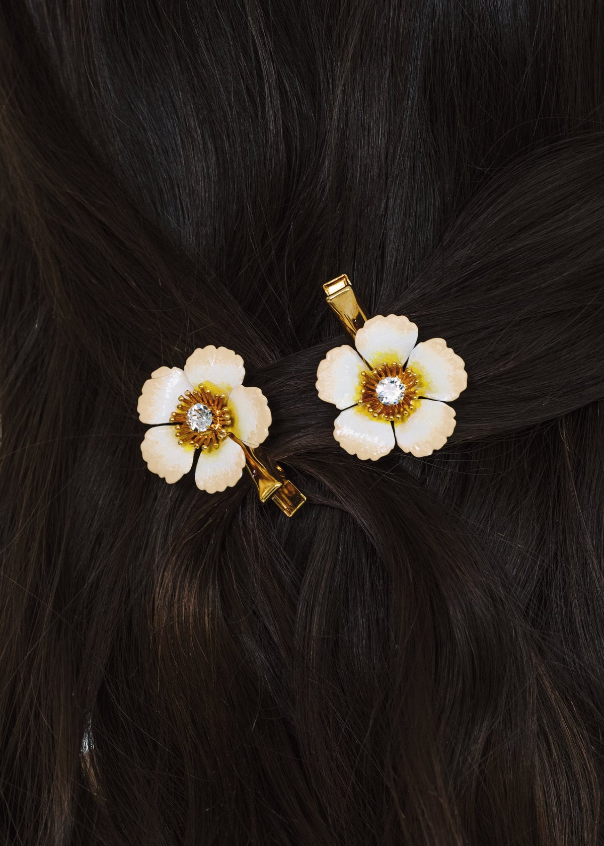 Close-up of Debbie Hair Clips in Champagne showcasing hand-painted flowers with crystal centers on dark hair
