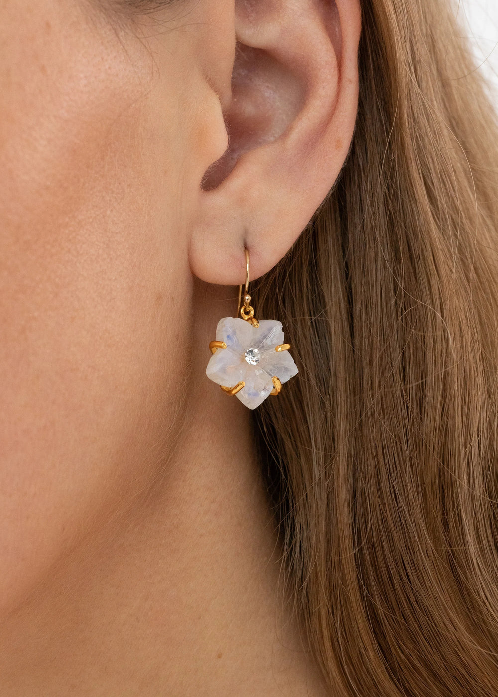 Close-up of Lyanna moonstone earrings, hand-carved flower moonstone drop with gold-plated prongs and center crystal