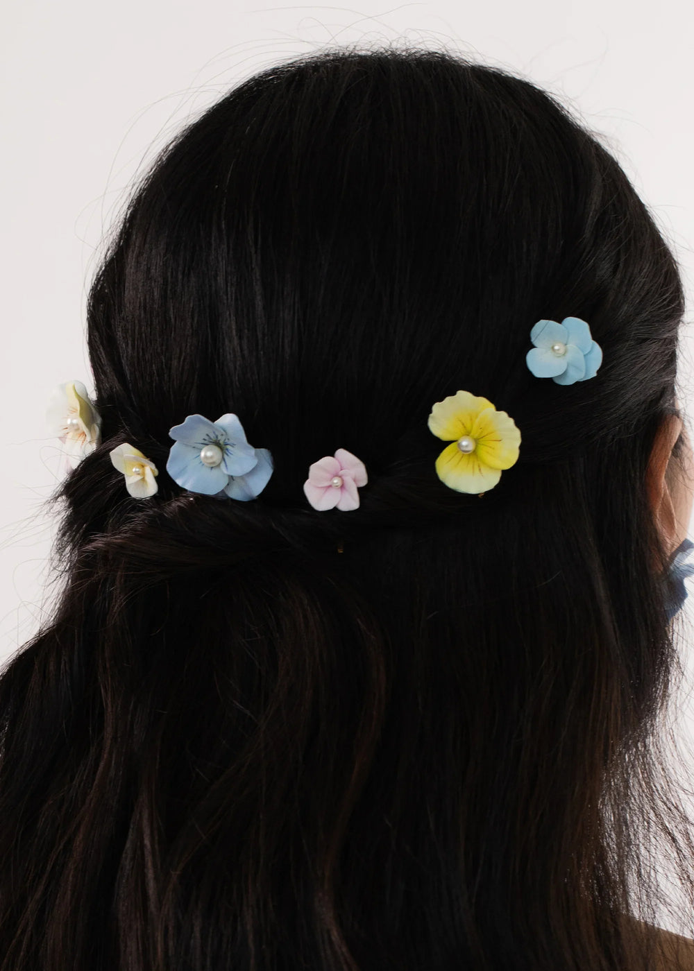 Back view of Anarosa Bobby Pins set showing pastel clay flowers with pearl centers pinned in dark hair