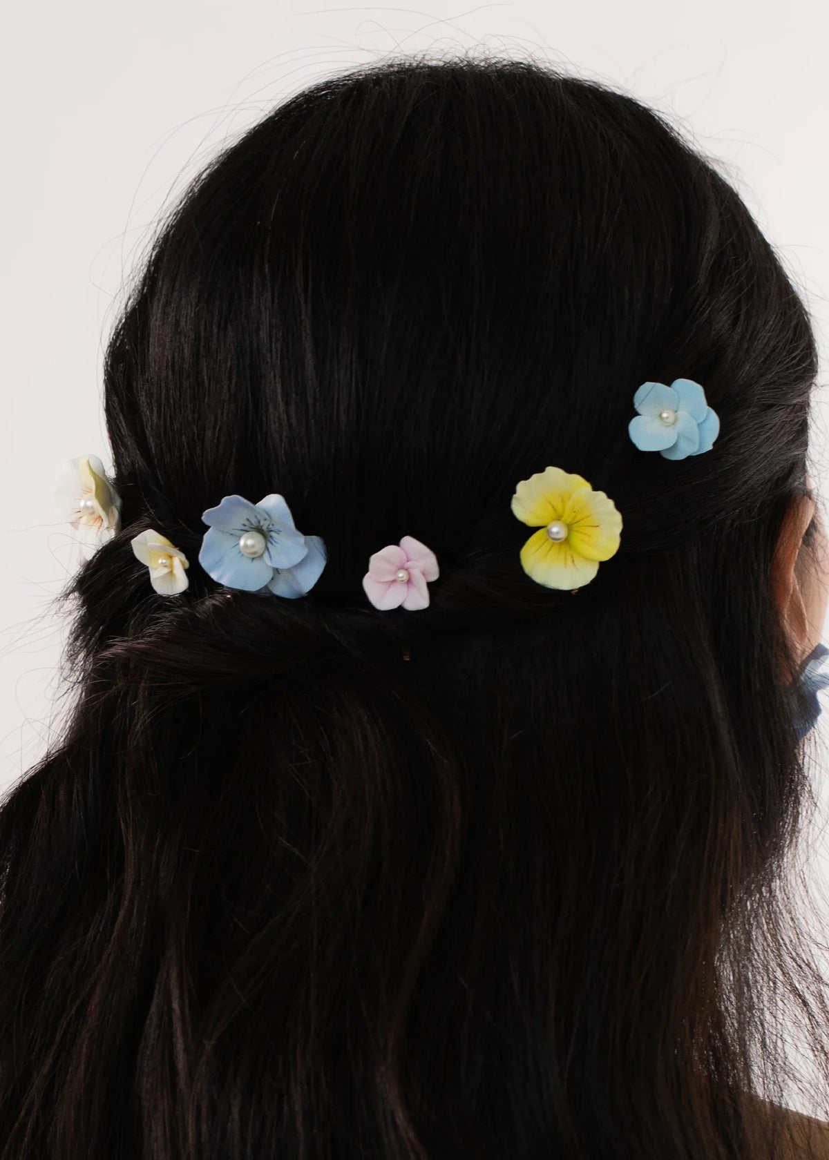 Back view of Anarosa Bobby Pins set showing pastel clay flowers with pearl centers pinned in dark hair