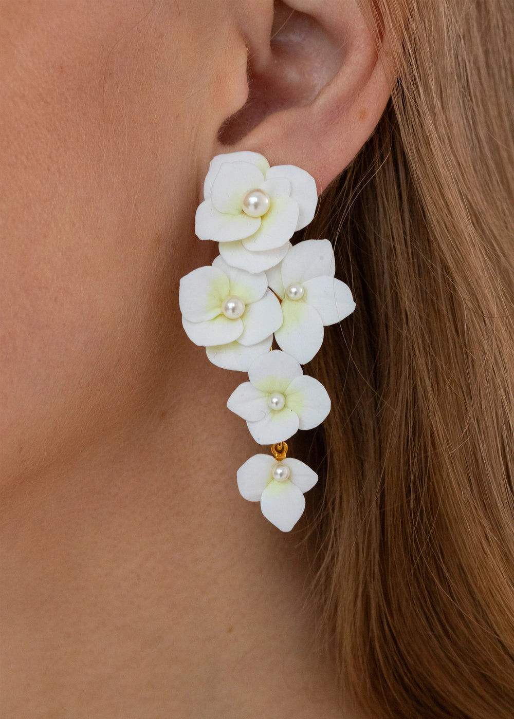 Close-up side view of Elowen Earrings in cream showing cascading clay hydrangea petals with pearl centers on model’s ear