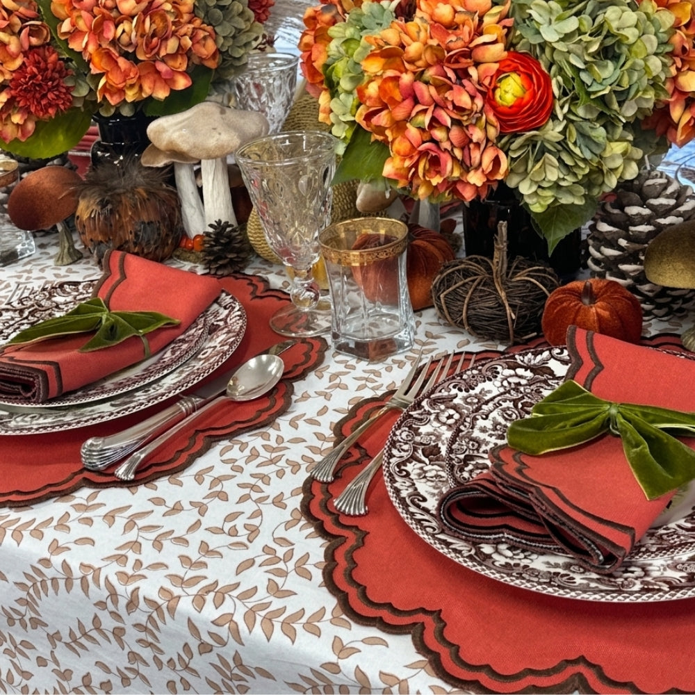 An autumn-themed table setting featuring burnt orange scalloped placemats and  matching napkins with brown embroidery, Thanksgiving table, luxury placemats
