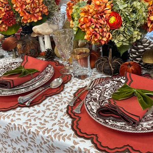 An autumn-themed table setting featuring burnt orange scalloped placemats and  matching napkins with brown embroidery, Thanksgiving table, luxury placemats