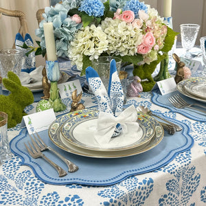 Elegant Easter  table setting with floral centerpiece, blue and white tablecloth, and silverware.