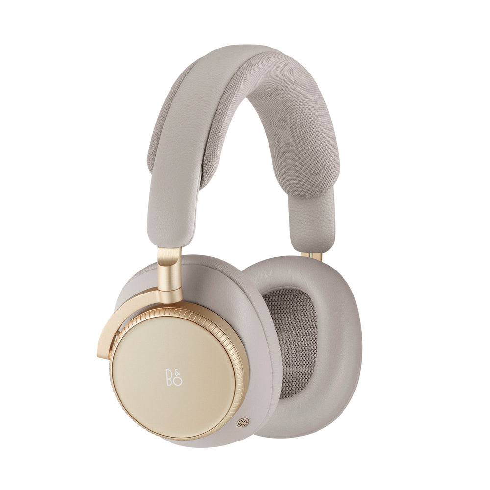 Three-quarter view of Beoplay H100 headphones in Hourglass Sand with gold accents and cushioned earcups on white