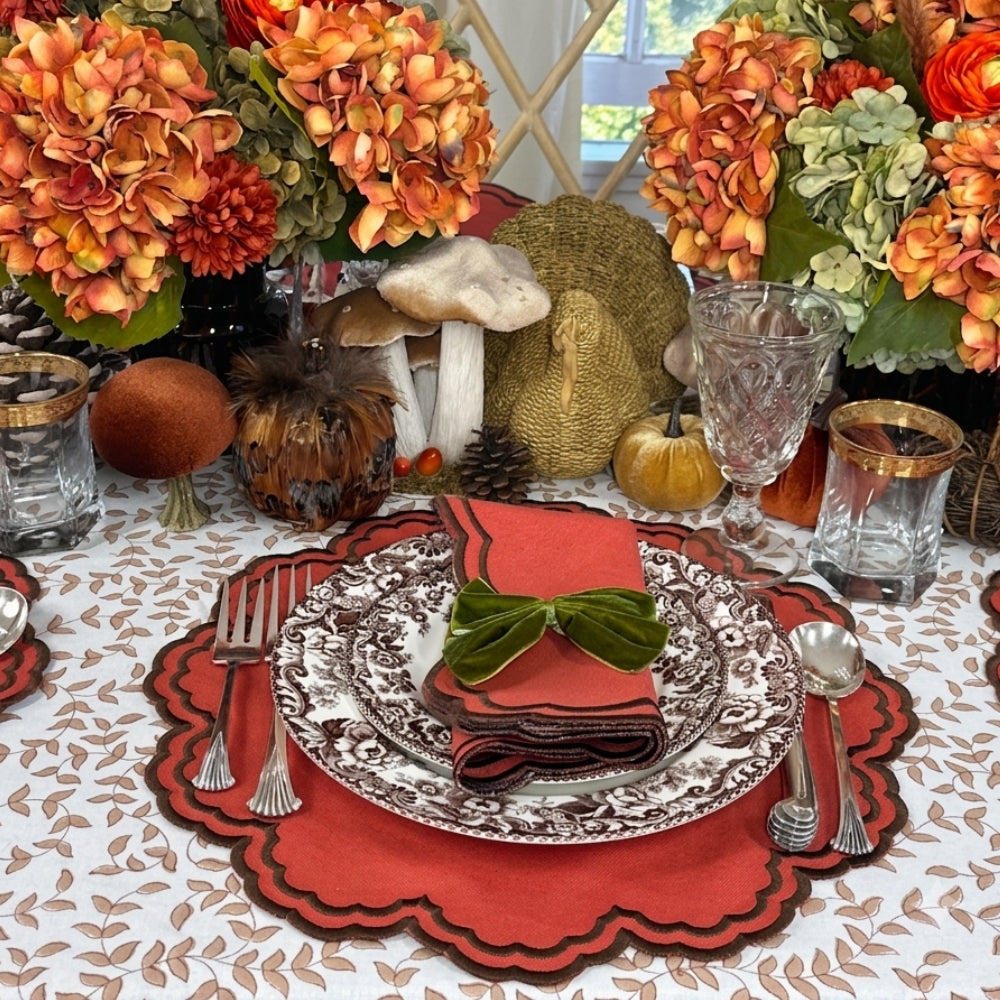 An autumn-themed table setting featuring burnt orange scalloped placemats and  matching napkins with brown embroidery, Thanksgiving table, luxury placemats