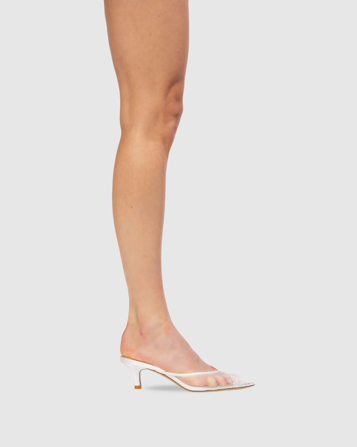Side view of Cara 50 mule in white mesh with pointy toe, sheer satin upper and low curved kitten heel on light gray