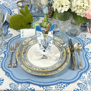 Elegant Easter table setting with floral centerpiece, blue and white tablecloth, and silverware.