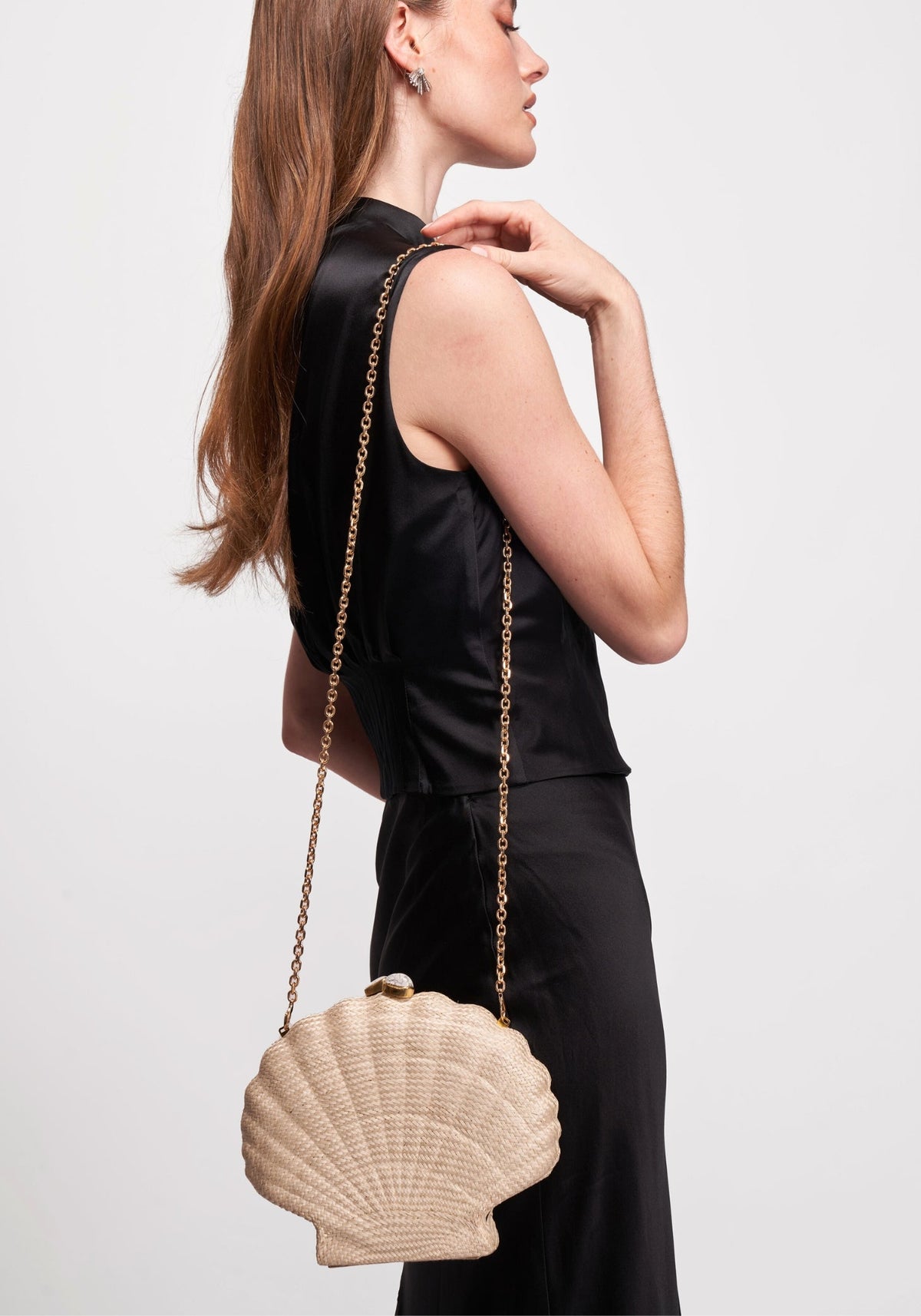 Side view of Le Sirenuse shell bag in natural showing woven buntal texture, white stone closure, and gold chain on model