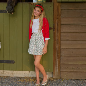 Girls’ Sutton Skirt in Regent Wreaths, featuring a festive green wreath and red star print on white with a full gathered silhouette.