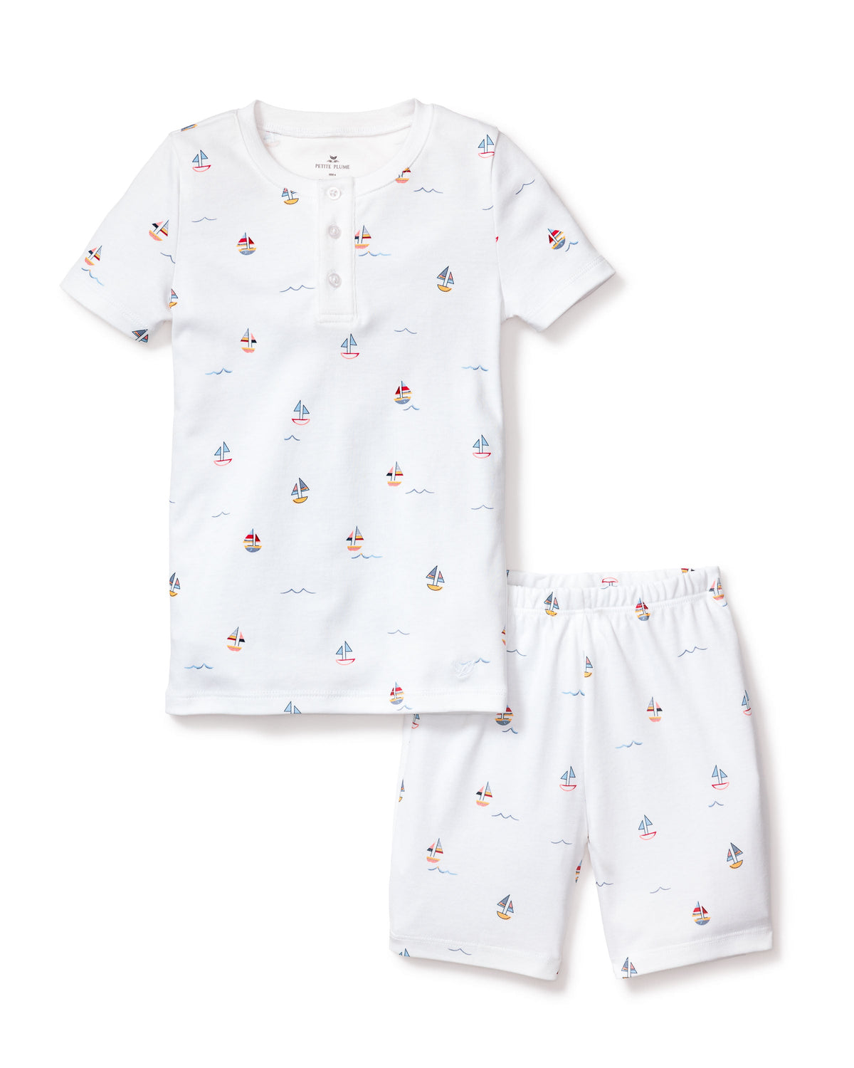 Flat lay of kids’ Pima short pajama set: white henley top with button placket and elastic waist shorts in small sailboat print