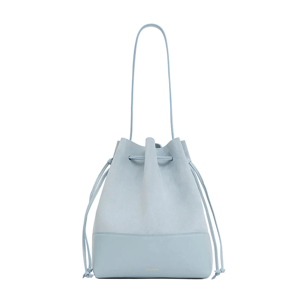 Front view of Drawstring Cabas in baby blue suede with leather base, drawstring closure and shoulder strap on white