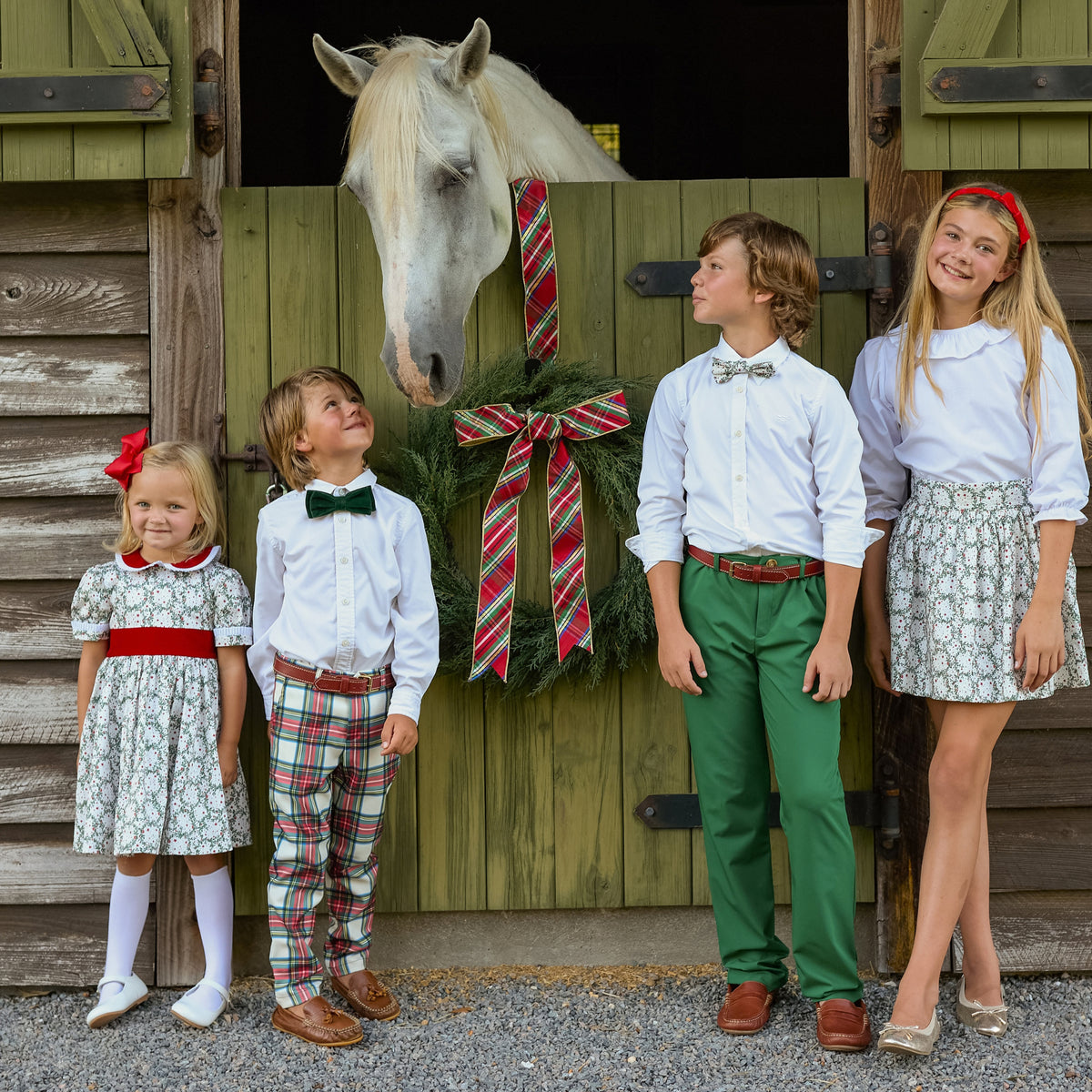 Children pose with a horse outside a barn, including a boy wearing a green bow tie