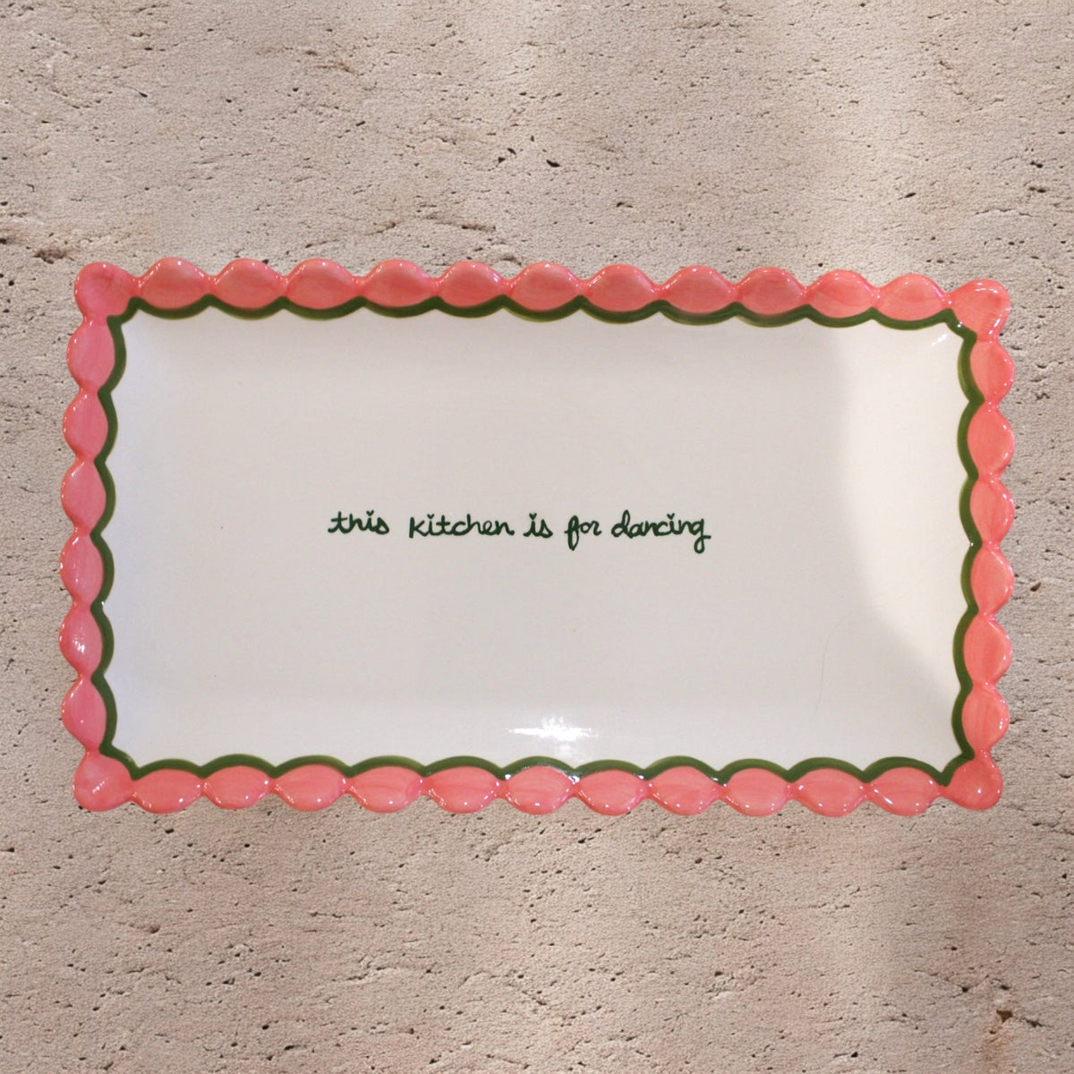 Top view of hand-painted scalloped tray with pink edges, green trim, and This Kitchen is for Dancing lettering