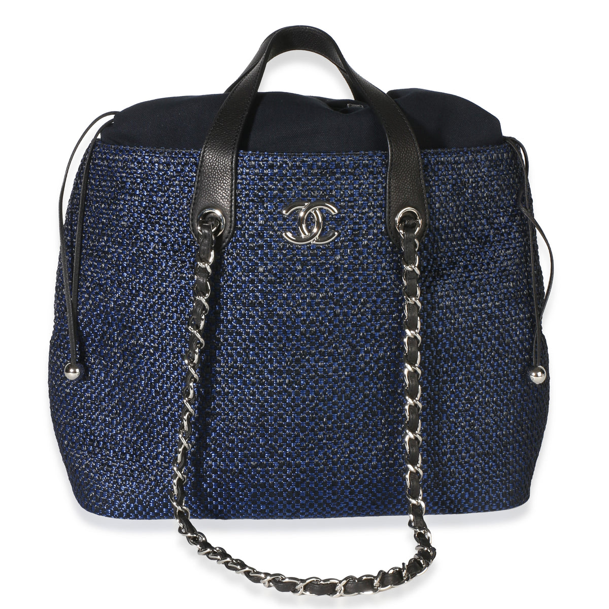 Front view of Chanel navy blue raffia CC expandable tote with silver tone logo and drawstring closure on white background