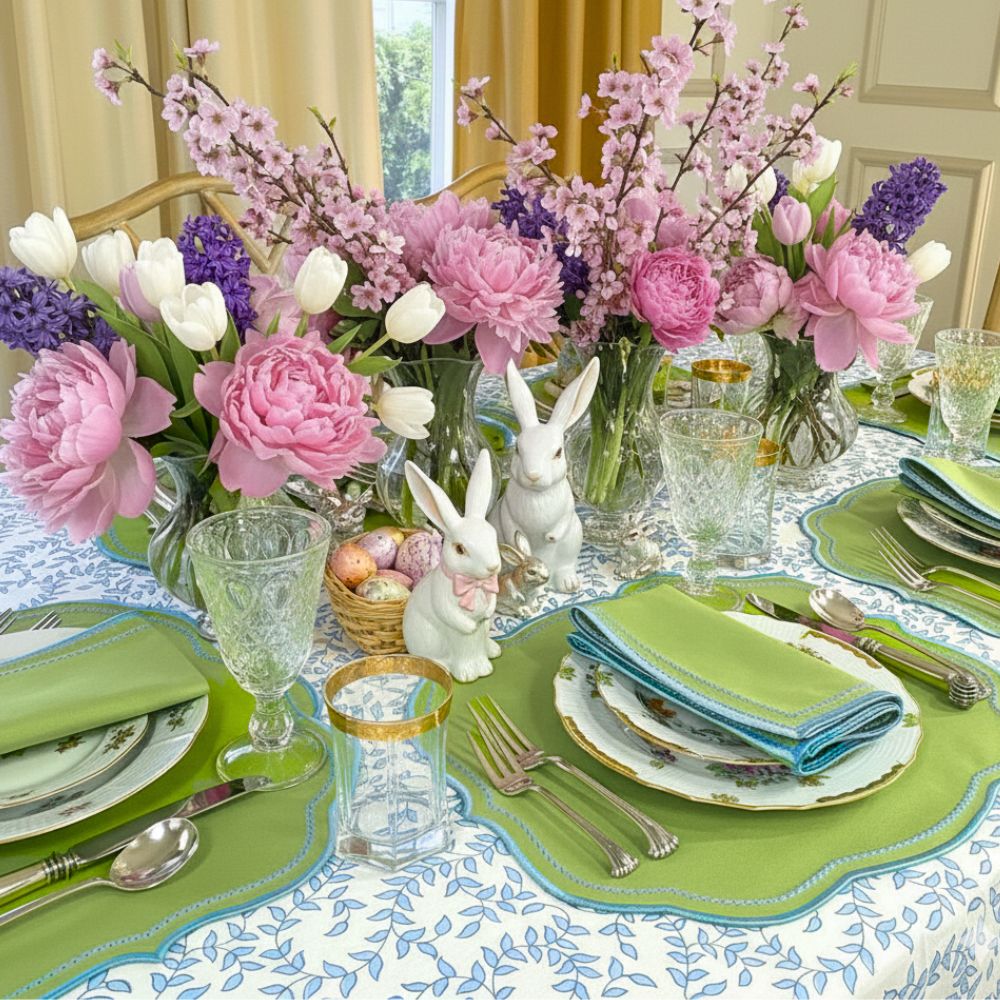 Easter-themed table setting with flowers, bunny figurines, and colorful plates.