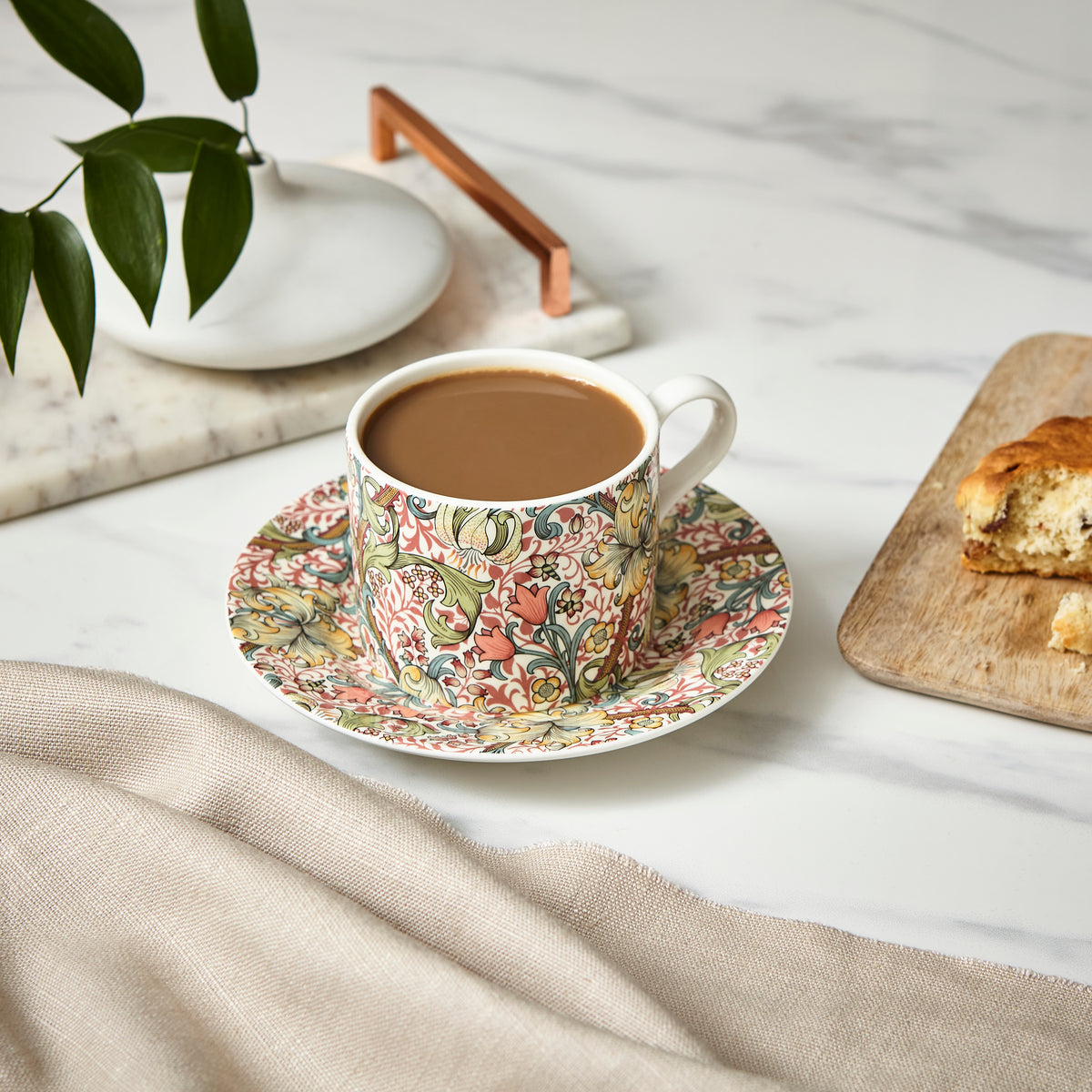 Close up of Morris & Co. Teacup & Saucer in Golden Lily showing lilies and intertwining stems with coffee on a white table