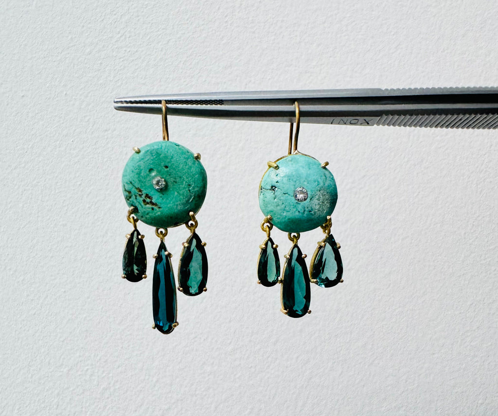 Front view of ancient turquoise, diamond and tourmaline earrings with round turquoise stones and dangling tourmaline on a light background