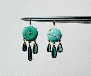 Front view of ancient turquoise, diamond and tourmaline earrings with round turquoise stones and dangling tourmaline on a light background