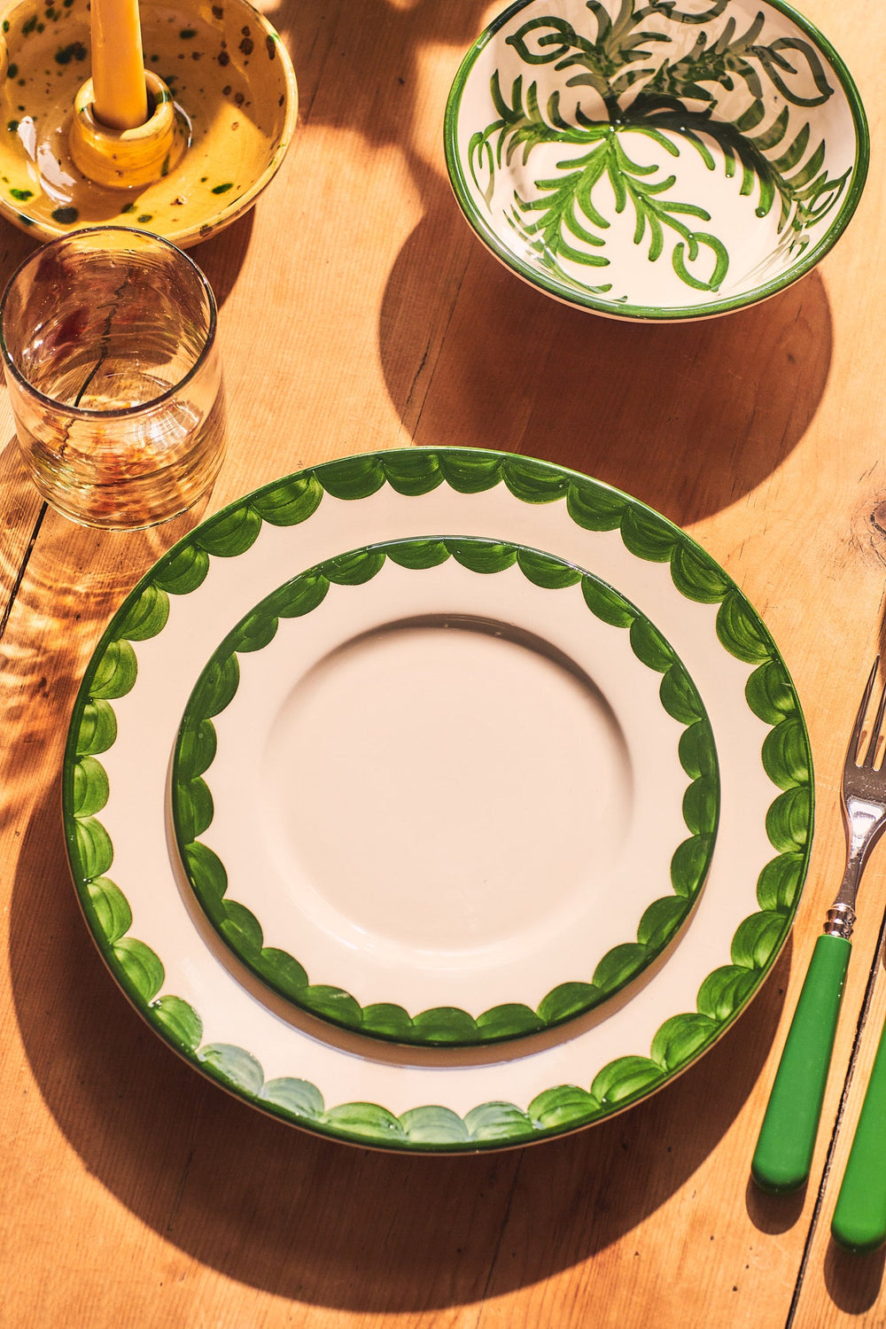 Top-down view of Green Scallop side plate showcasing hand-painted scalloped green rim on a wooden table