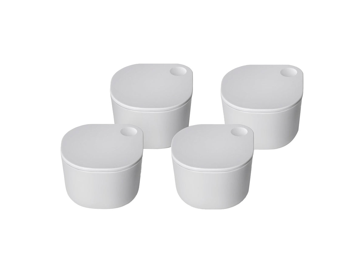 Three-quarter view of four white Dot containers with matching lids showing small circular indentations on a white background