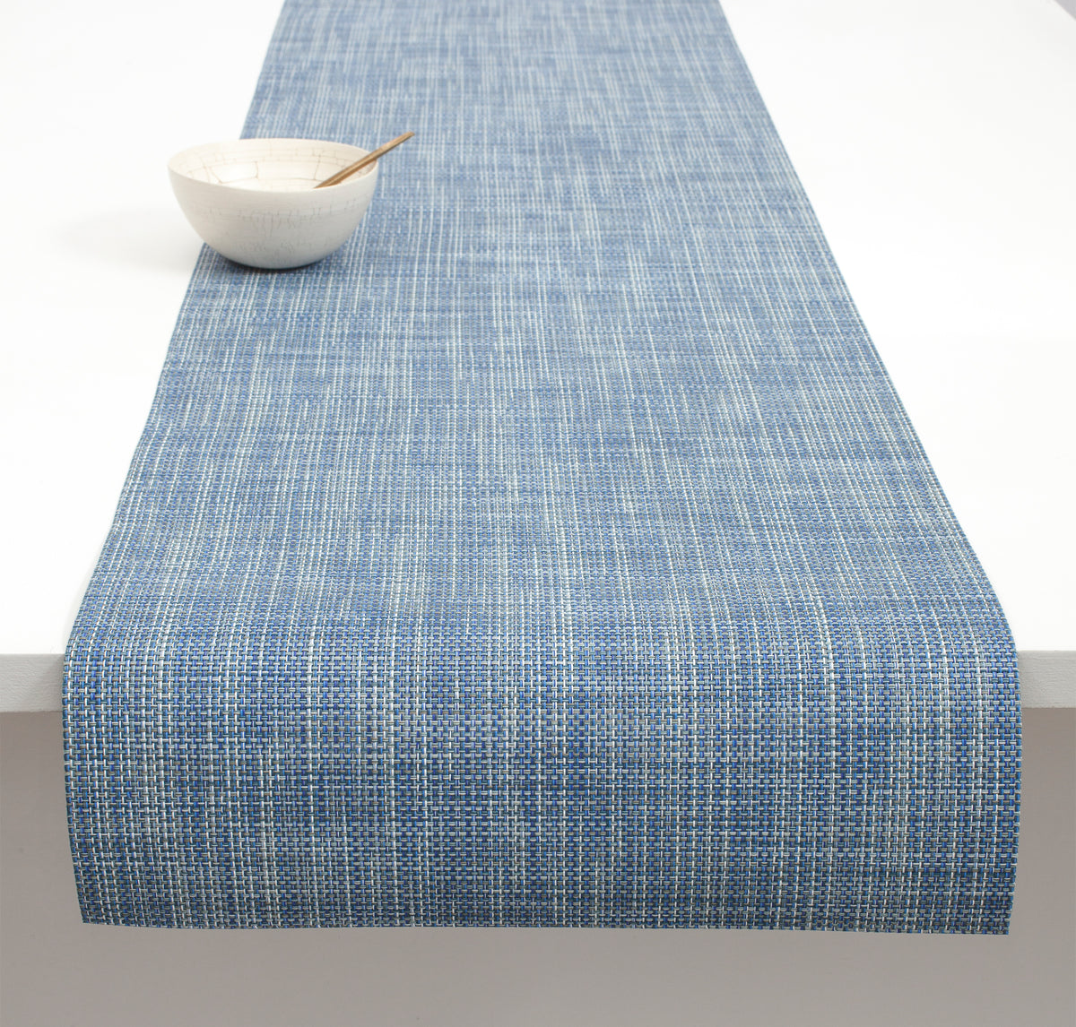 Angled view of Mini Basketweave Table Runner showcasing blue woven texture on a white table