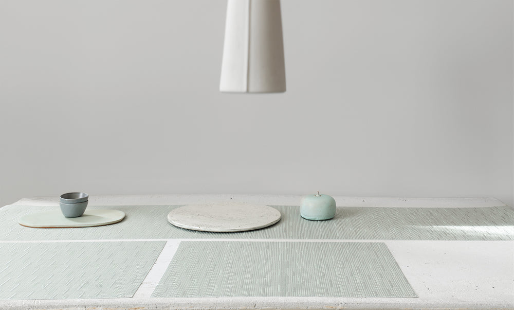 Angled view of Bamboo rectangular placemat in seaglass showing textured bamboo weave on stone tabletop with ceramic props