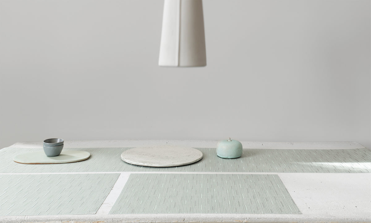 Angled view of Bamboo rectangular placemat in seaglass showing textured bamboo weave on stone tabletop with ceramic props