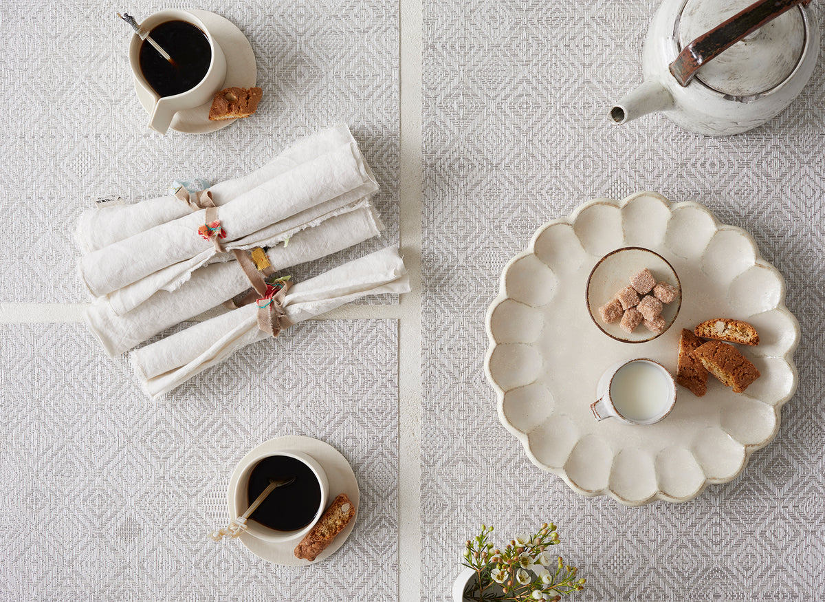 Top-down view of gray Mosaic Placemat showcasing a textured diamond weave beneath cups, napkins, and a serving plate