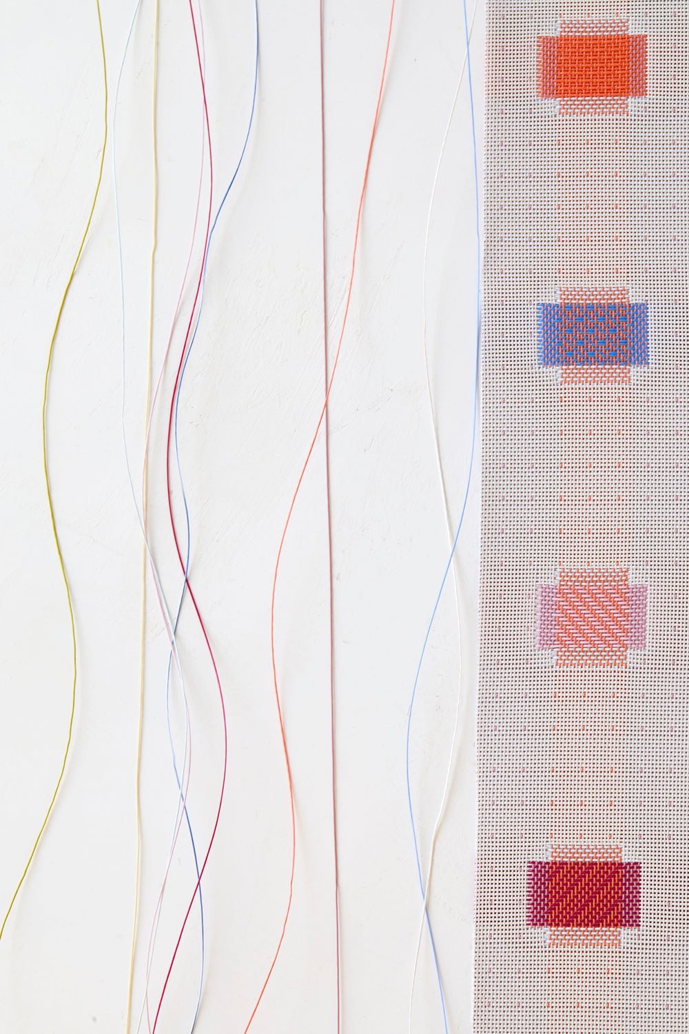 Close-up of Sampler Table Runner showcasing multicolored woven square motifs and trailing colorful yarns on a white background