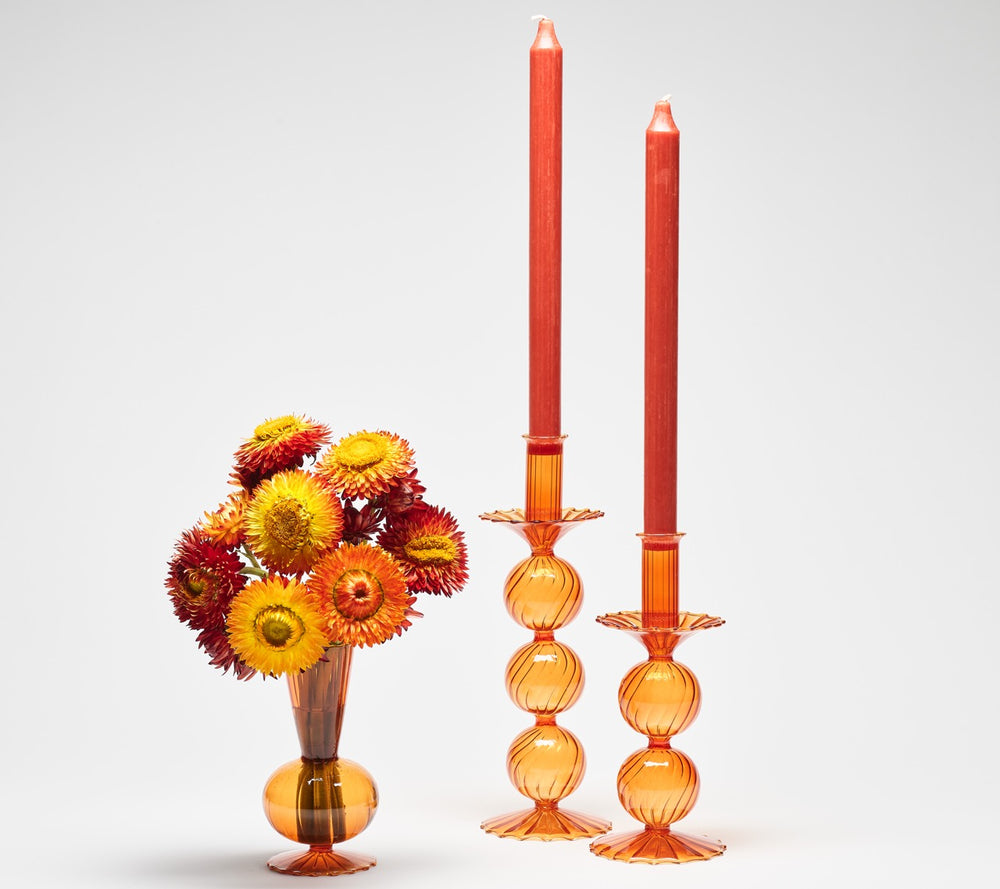 Front view of Bella Short candle holders in amber, set of 2, showcasing stacked-globe design and scalloped bases with two tall taper candles on a white background